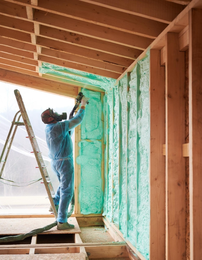 Technicien appliquant une mousse isolante sur une ossature en bois