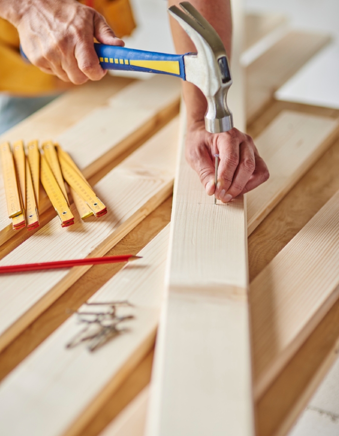 Menuisier fixant une planche de bois avec un marteau