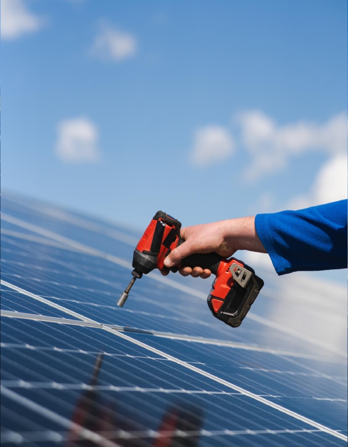 Technicien fixant un panneau solaire avec une visseuse